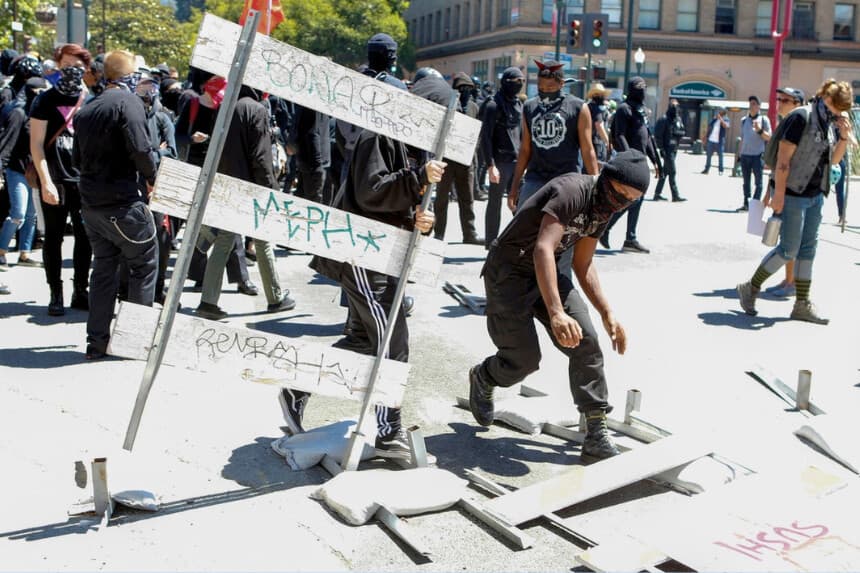 Militantes antifa derriban barricadas callejeras mientras marchan con contramanifestantes durante una manifestación de la alt-right en el centro de Berkeley, California, el 5 de agosto de 2018. (Amy Osborne/AFP/Getty Images).