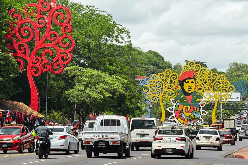 El tráfico circula junto a las estructuras metálicas conocidas como "Árboles de la Vida", que rodean una imagen del difunto expresidente venezolano Hugo Chávez, en una glorieta que lleva su nombre en Managua, el 28 de junio de 2026. (AFP vía Getty Images)