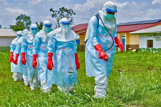 Los trabajadores de la Cruz Roja caminan en formación mientras desinfectan el hospital general de Rwampara antes de manipular el cuerpo de una persona fallecida de ébola, mientras las agencias de ayuda intensifican los esfuerzos para contener un nuevo brote de ébola relacionado con la cepa Bundibugyo, en Rwampara, a las afueras de Bunia, provincia de Ituri, República Democrática del Congo, el 21 de mayo de 2026. (Gradel Muyisa Mumbere/Reuters).