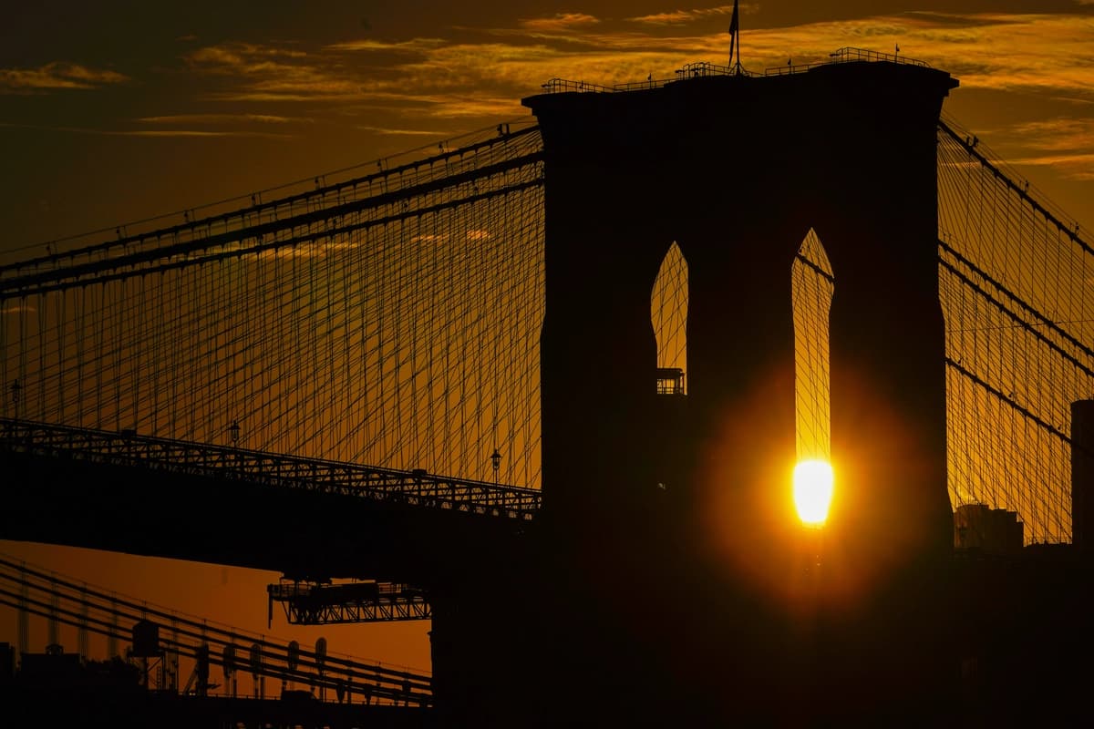 El sol sale tras el puente de Brooklyn el 11 de octubre de 2023 en Nueva York. (Kiichiro Sato/AP Photo).