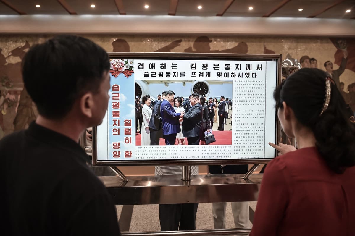 Varias personas observan una pantalla con el periódico "Rodongsinmun", que muestra noticias sobre la visita del presidente chino Xi Jinping, en la estación Kaeson del metro de Pyongyang, el 9 de junio de 2026. (Kim Won Jin / AFP vía Getty Images).