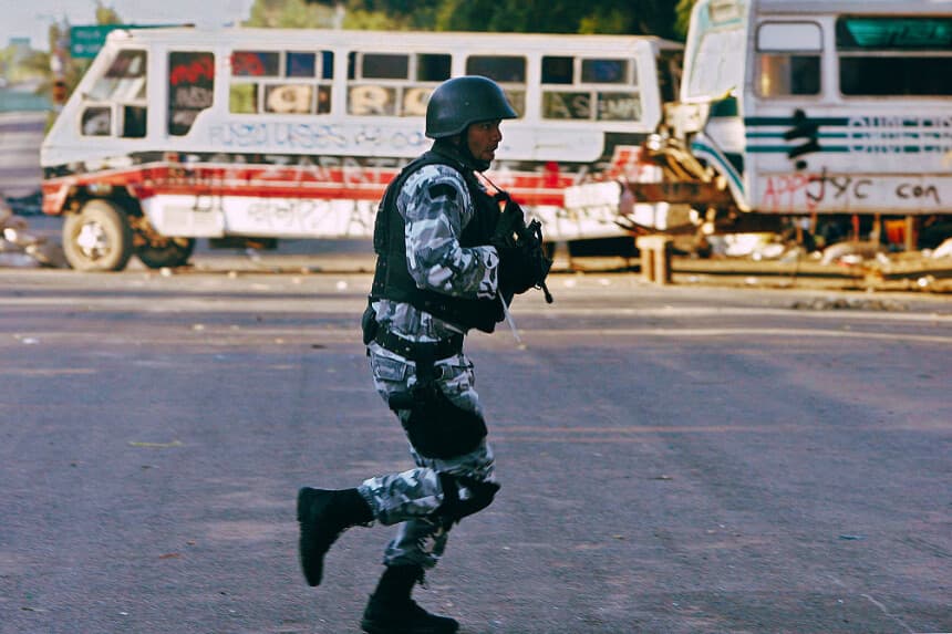 Un miembro de las fuerzas de operaciones especiales corre durante la recuperación de la carretera México-Oaxaca, el 1 de noviembre de 2006. (ALFREDO ESTRELLA/AFP vía Getty Images)