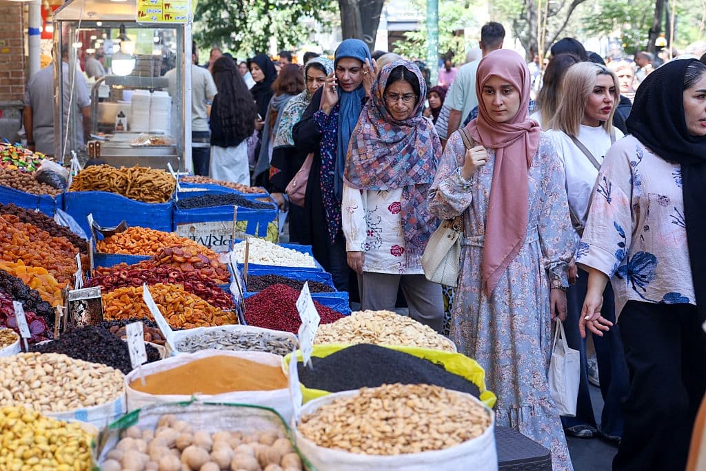 La gente pasa junto a las tiendas en una zona comercial de Teherán el 24 de agosto de 2026. (AFP vía Getty Images)