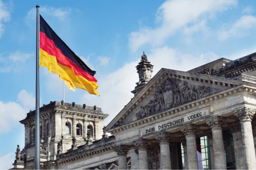 La bandera alemana ondeando sobre el edificio del Reichstag en Berlín, Alemania. (Maheshkumar Painam/Unsplash.com).