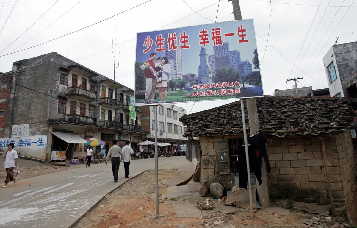 Un cartel publicitario que promueve la política del "hijo único" y que dice "Ten menos hijos, vive mejor" recibe a los residentes en la calle principal de Shuangwang, en la región de Guangxi, al sur de China, en mayo de 2017. (Goh Chai Hin/AFP vía Getty Images)