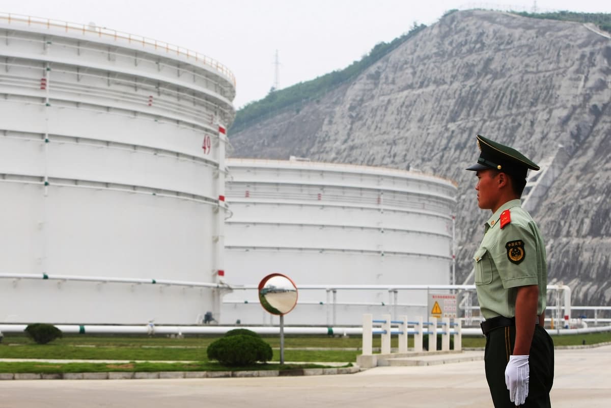 Un guardia de seguridad se encuentra cerca de grandes tanques de petróleo en la Base Nacional de Reservas Petroleras de Zhenghai, en Ningbo, provincia de Zhejiang, China, el 3 de junio de 2009. (Feng Li/Getty Images)