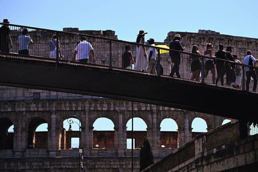 Varias personas caminan por un puente cerca del Coliseo en Roma, el 6 de agosto de 2026. (Tiziana FABI / AFP vía Getty Images)