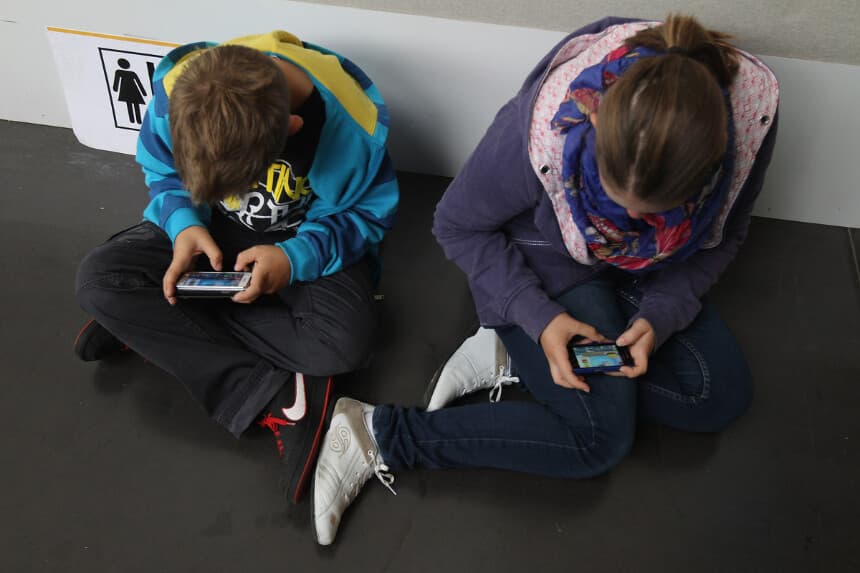 Unos niños juegan videojuegos en sus teléfonos inteligentes mientras asisten a un evento público el 22 de septiembre de 2012 en Ruesselsheim, Alemania. (Sean Gallup/Getty Images)
