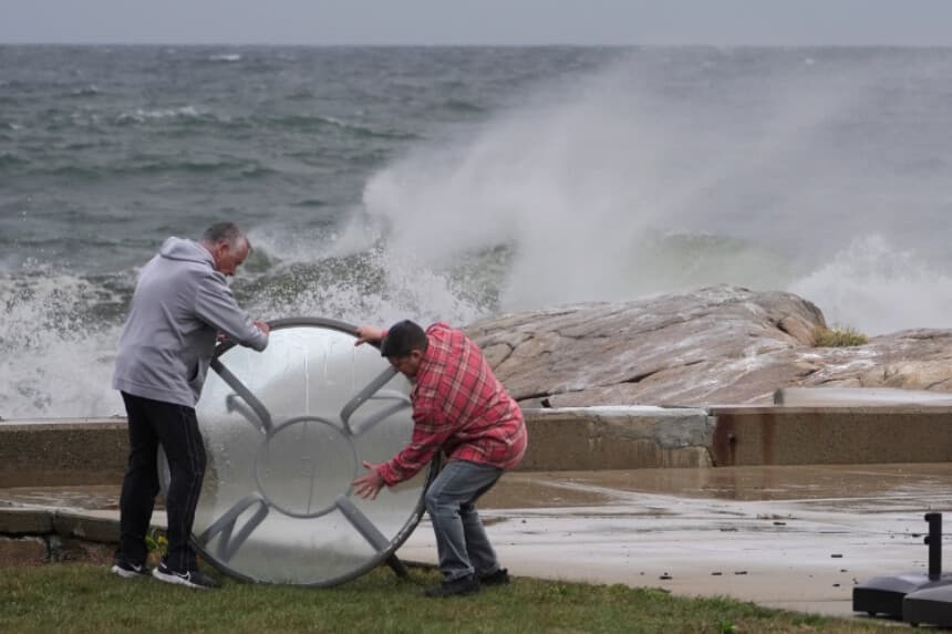 Unos residentes retiran una mesa de exterior de la orilla durante las primeras fases de una tormenta del noreste en Gloucester, Massachusetts, el 25 de septiembre de 2026. (Robert F. Bukaty/AP Photo).