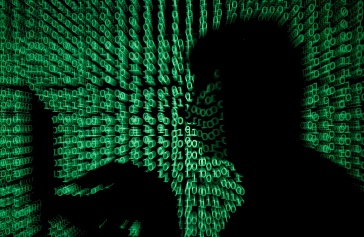 En esta ilustración, tomada el 13 de mayo de 2017, un hombre sostiene una computadora portátil mientras se proyecta código cibernético sobre él. (Reuters/Kacper Pempel).