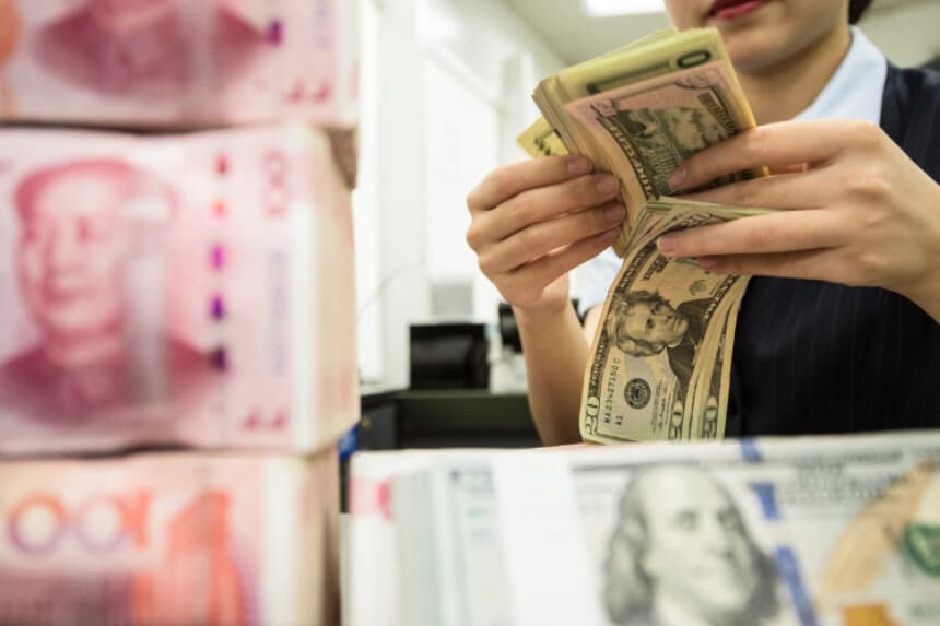 Un empleado de un banco chino cuenta billetes de 100 yuanes y dólares estadounidenses en la ventanilla de un banco en Nantong, en la provincia oriental de Jiangsu (China), el 6 de agosto de 2019. (STR/AFP vía Getty Images).