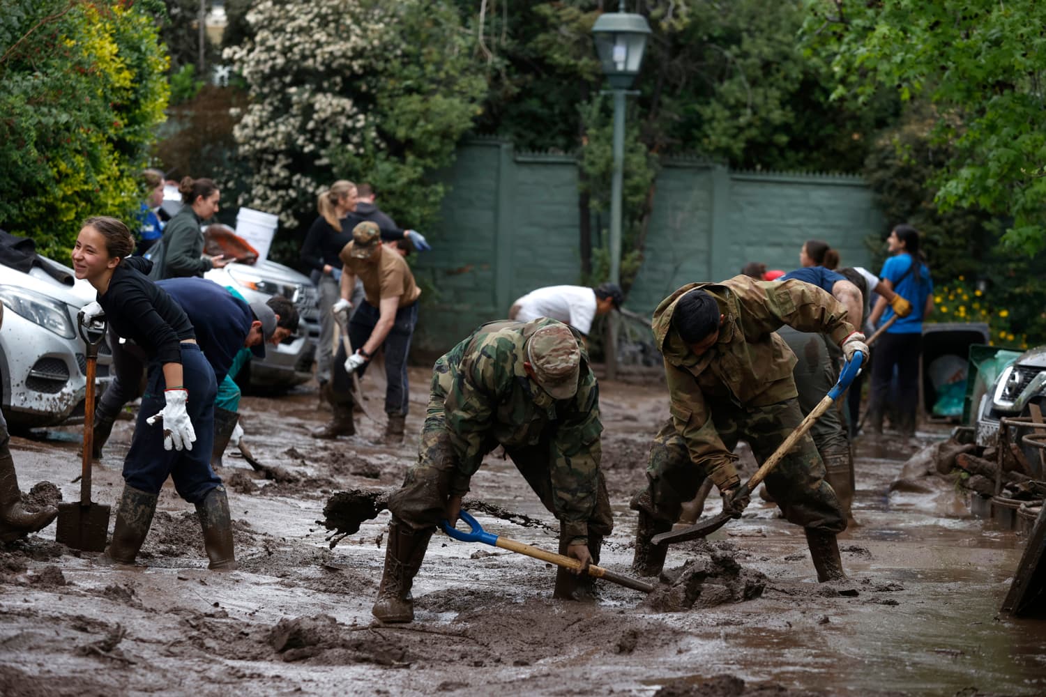 Integrantes del Ejército de Chile trabajan en la remoción de lodo tras el paso de un aluvión en la comuna de Las Condes este viernes, en Santiago (Chile). Un aluvión por intensas lluvias que afectó a la comuna Las Condes, en el este de Santiago, y generó el arrastre de vehículos y buses en las calles, dejó 6 personas lesionadas y 600 hogares evacuados, informó el ministro del Interior de Chile, Claudio Alvarado. (EFE/ Elvis González)