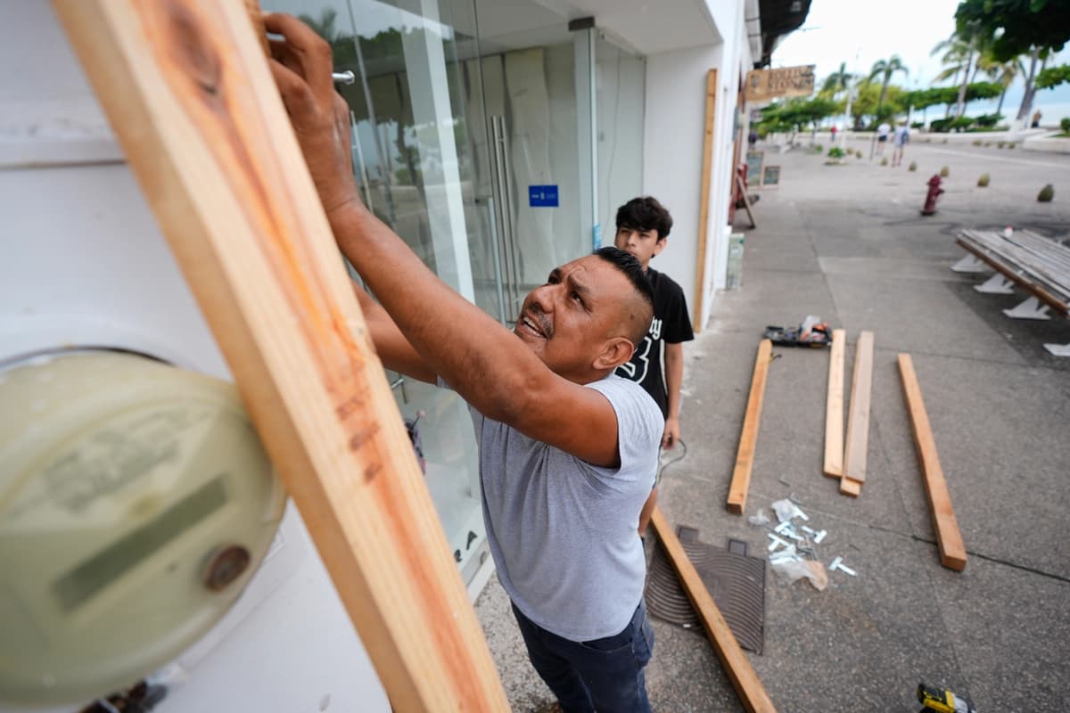 Un hombre tapia una tienda mientras el huracán Simón se acerca a Puerto Vallarta, México, el sábado 10 de octubre de 2026. (Foto AP/Fernando Llano).