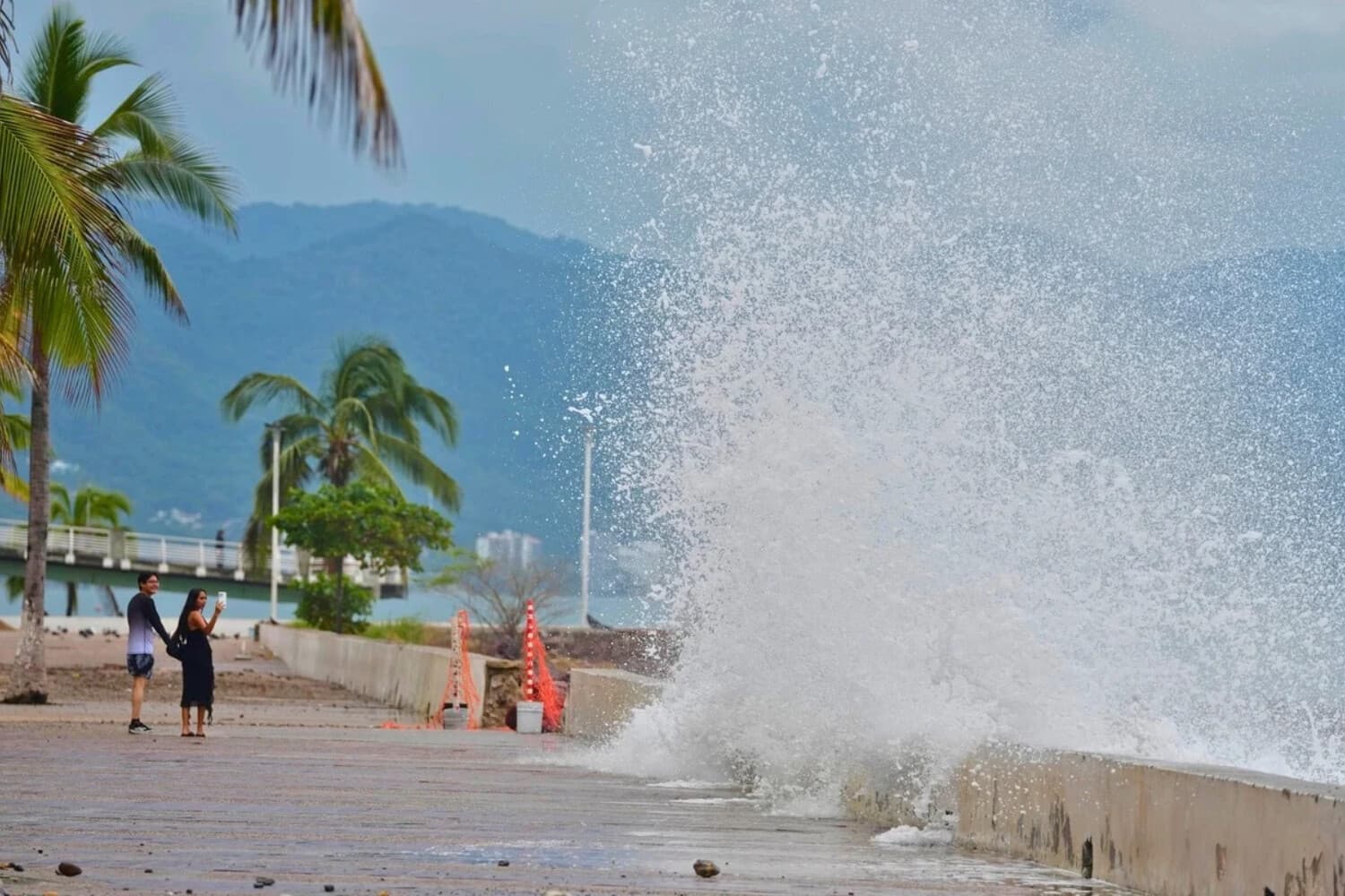 Turistas hacen fotos de un agua salpicando contra la pared mientras el huracán Simón se acerca a Puerto Vallarta, México, el 11 de octubre de 2026. (Fernando Llano/AP Photo).