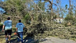 Voluntarios trabajan para retirar árboles caídos mientras comienza la recuperación tras el huracán Isaías