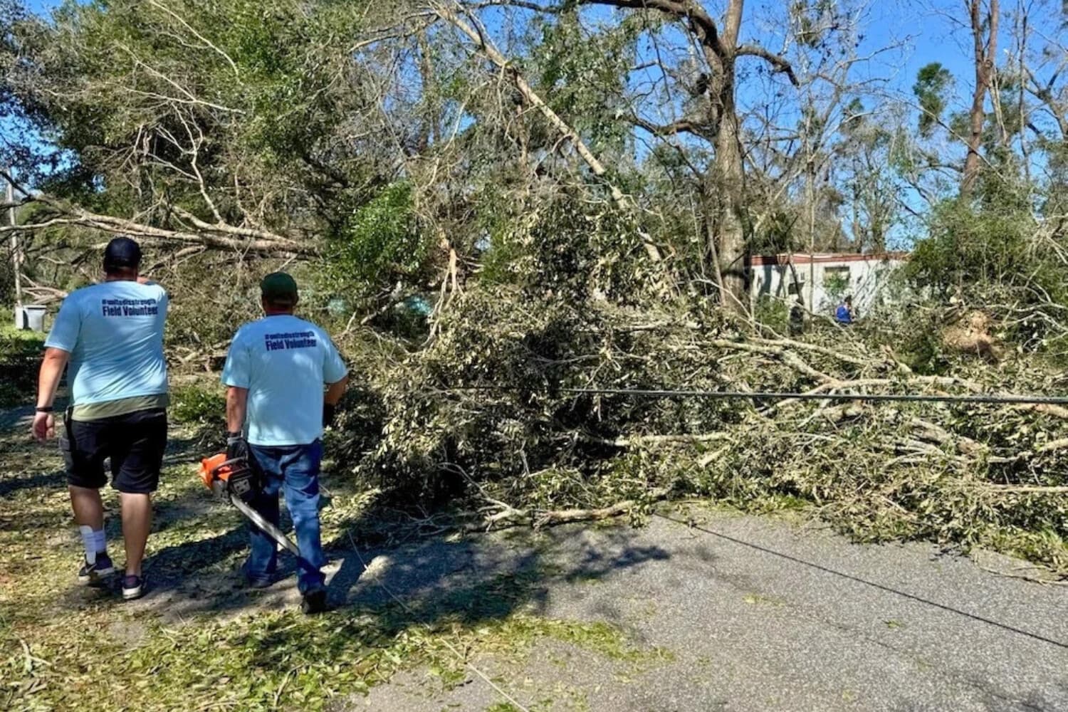 Voluntarios trabajan para retirar árboles caídos mientras comienza la recuperación tras el huracán Isaías