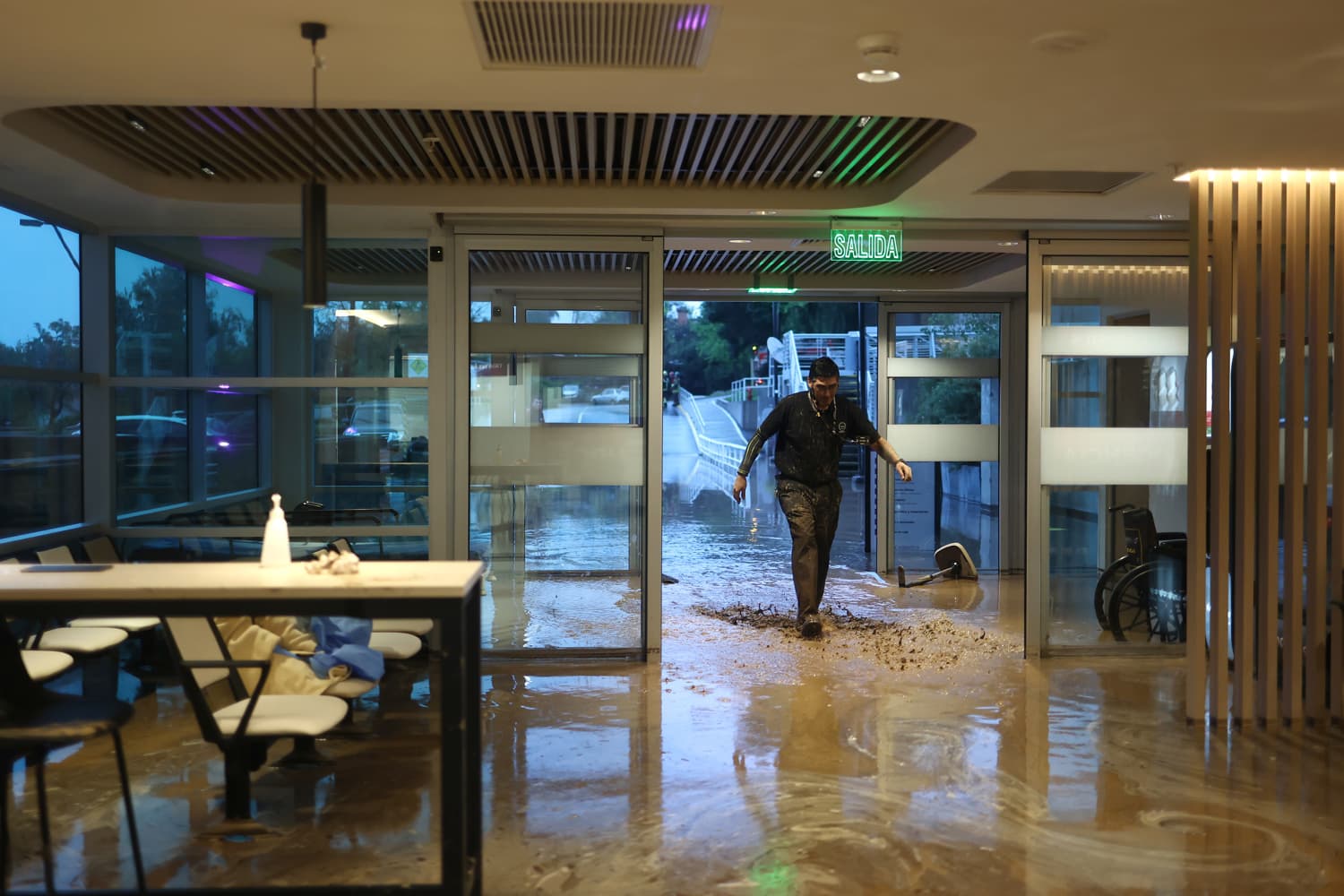 Un persona ingresa a la clínica San Carlos de Apoquindo afectada por un aluvión este jueves, en la comuna de Las Condes, en Santiago (Chile). Las autoridades chilenas informaron que, en medio de las fuertes lluvias que afectan la zona centro-sur del país, se produjo un aluvión en una zona precordillerana al este de Santiago, que arrastró vehículos y buses. (EFE/ Javier Torres)