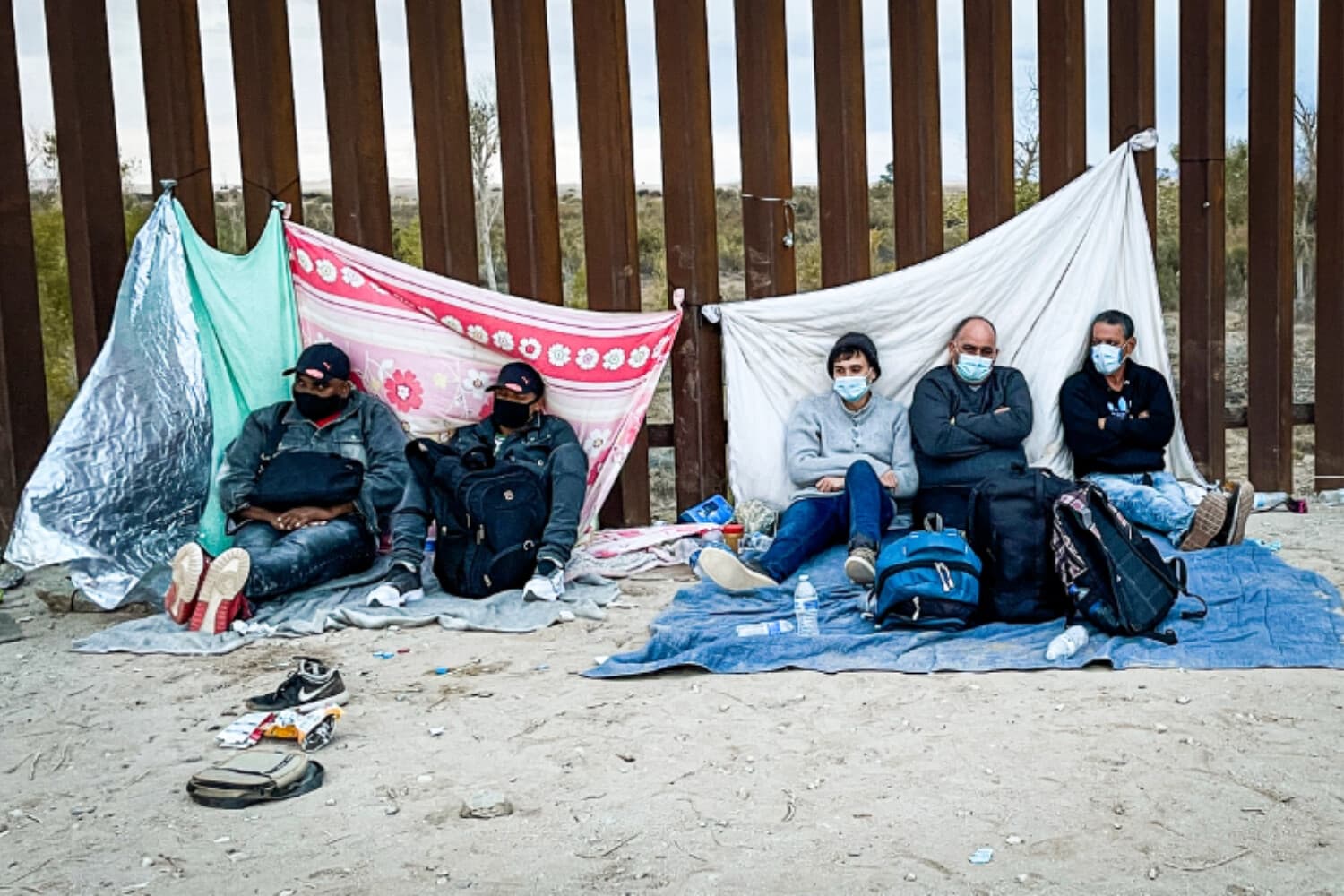 Inmigrantes ilegales esperan a la Patrulla Fronteriza junto a la valla fronteriza tras cruzar la frontera entre Estados Unidos y México en Yuma, Arizona, el 9 de diciembre de 2021. (Charlotte Cuthbertson/The Epoch Times).