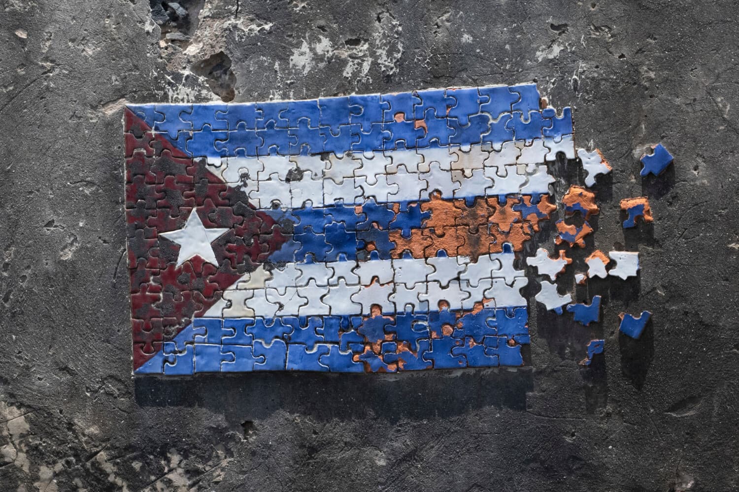 El 18 de junio de 2026 se observa un mosaico que representa la bandera cubana en forma de rompecabezas, armado con piezas de colores en una sección del muro de una fortificación costera a lo largo del malecón de La Habana. (Pablo PORCIUNCULA / AFP vía Getty Images)