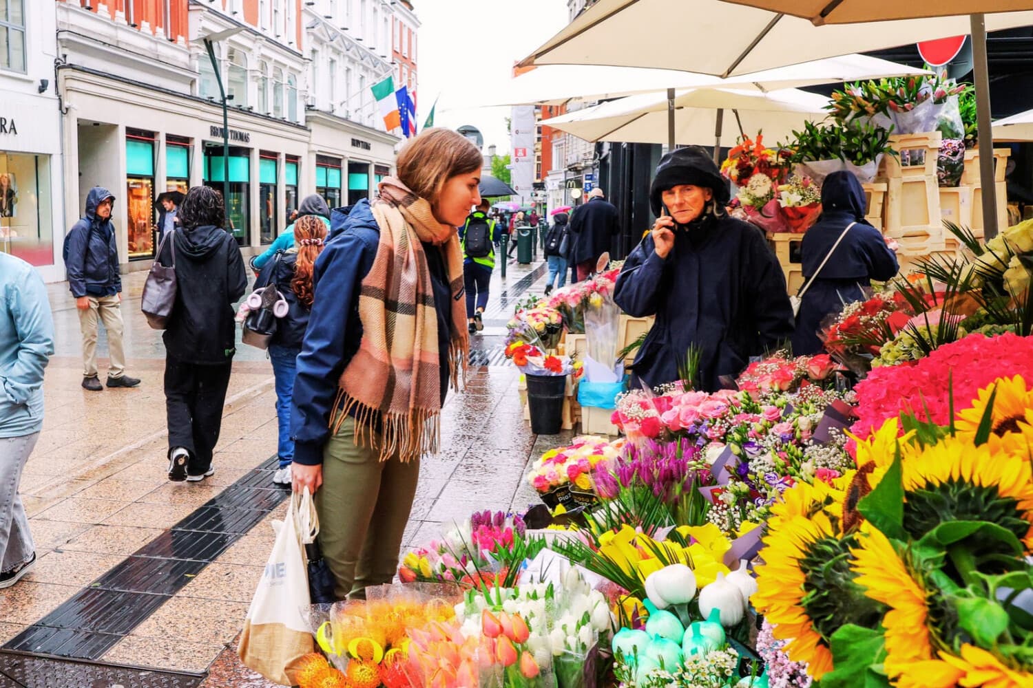 Los compradores caminan bajo la lluvia por Grafton Street, en el centro de Dublín, el 6 de octubre de 2026. (Paul Faith / AFP vía Getty Images)