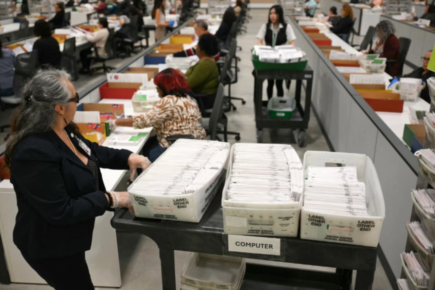 Un trabajador electoral traslada papeletas enviadas por correo en el Centro de Procesamiento de Votos del condado de Los Ángeles, durante las elecciones primarias estatales de California en City of Industry, el 2 de junio de 2026. (Patrick T. Fallon/AFP).