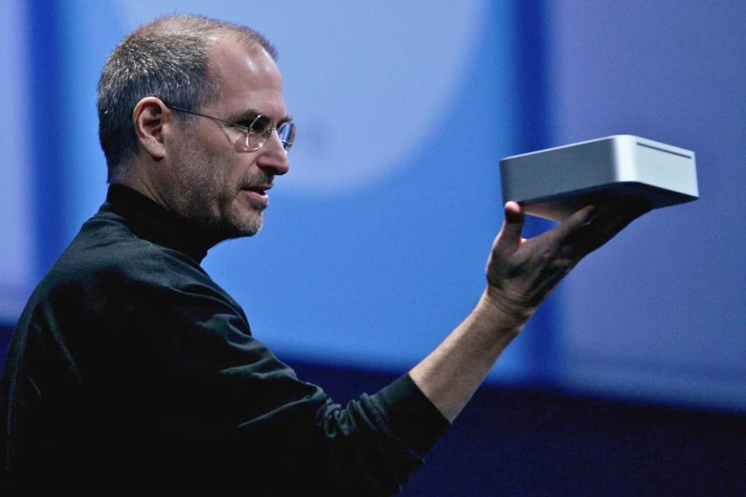 El entonces director ejecutivo de Apple, Steve Jobs, sostiene la computadora personal Mac Mini durante su discurso de apertura en la Macworld Expo, celebrada en San Francisco el 11 de enero de 2005. (Justin Sullivan/Getty Images).