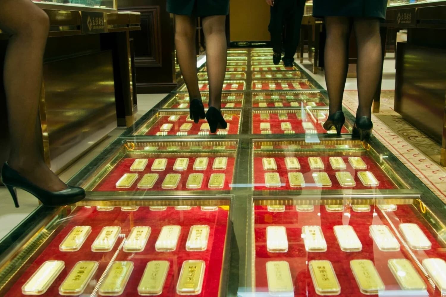 El personal de ventas chino camina por un pasillo pavimentado con lingotes de oro en una casa de intercambio de oro en Kunming, China, el 11 de diciembre de 2012. (STR/AFP/Getty Images).