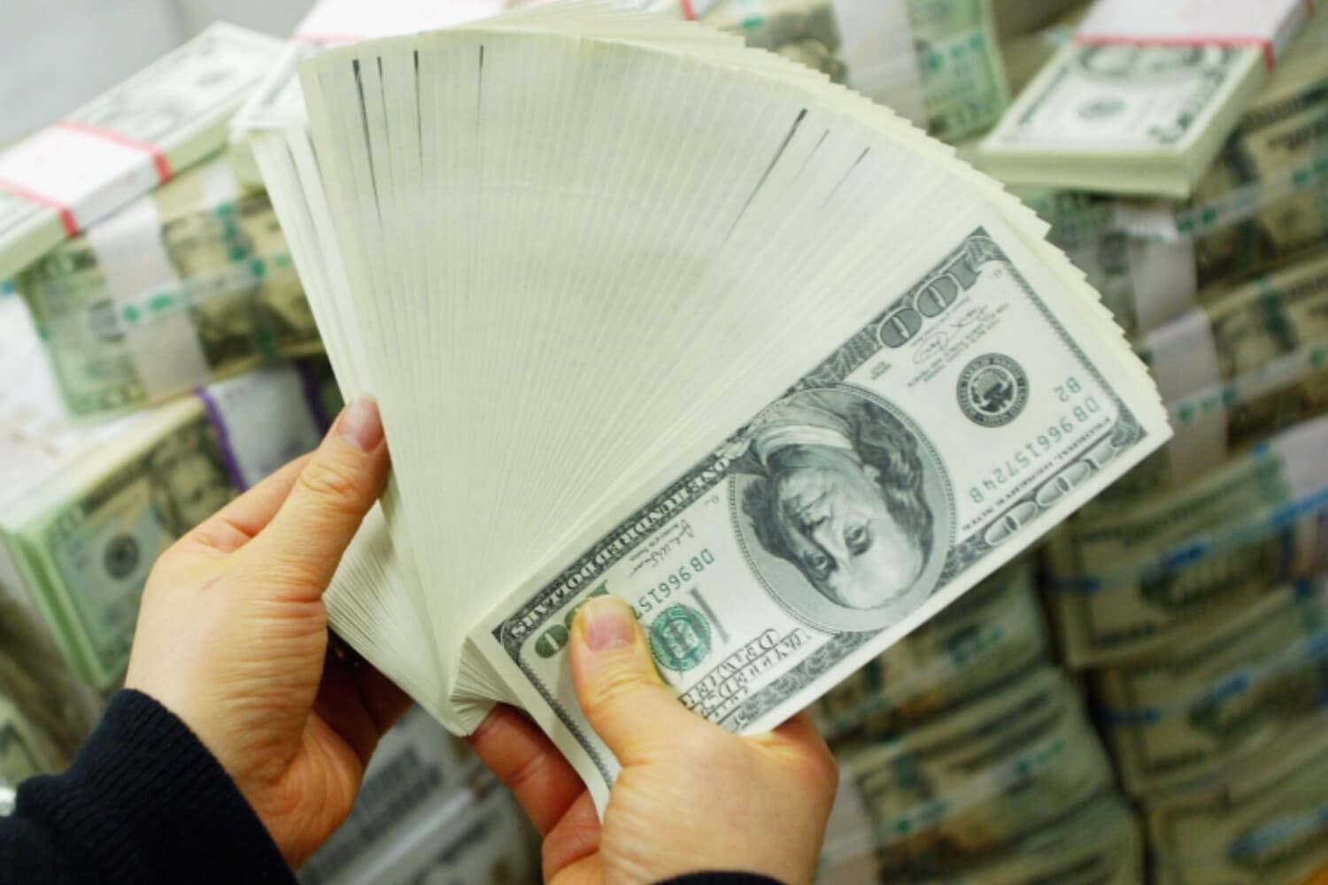 Un banquero surcoreano lleva billetes de dólar estadounidense en el Korea Exchange Bank en Seúl, Corea del Sur, el 22 de febrero de 2005. (Chung Sung-jun/Getty Images).