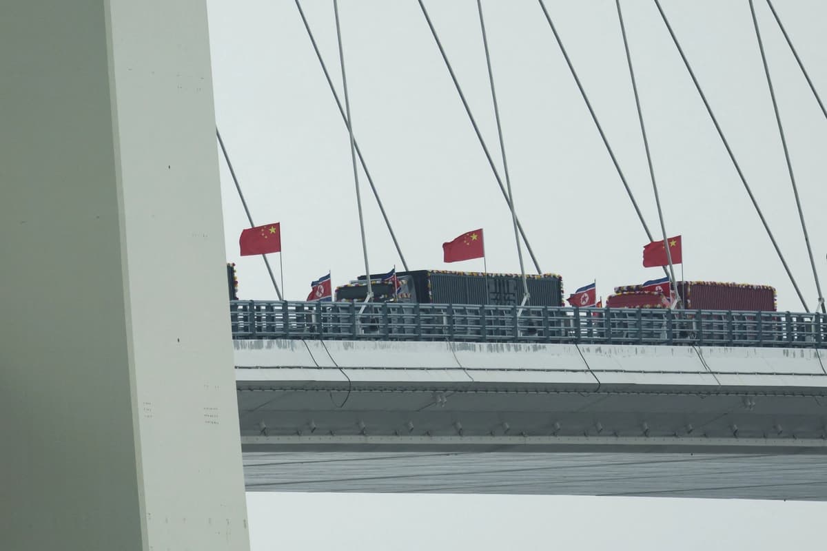 Camiones adornados con banderas norcoreanas entran en el lado chino del recién inaugurado Puente del Río Yalu, que conecta Sinuiju (Corea del Norte) con la Nueva Zona de Dandong (China), en Dandong, provincia de Liaoning (China), el 15 de octubre de 2026. (Florence Lo/Reuters)