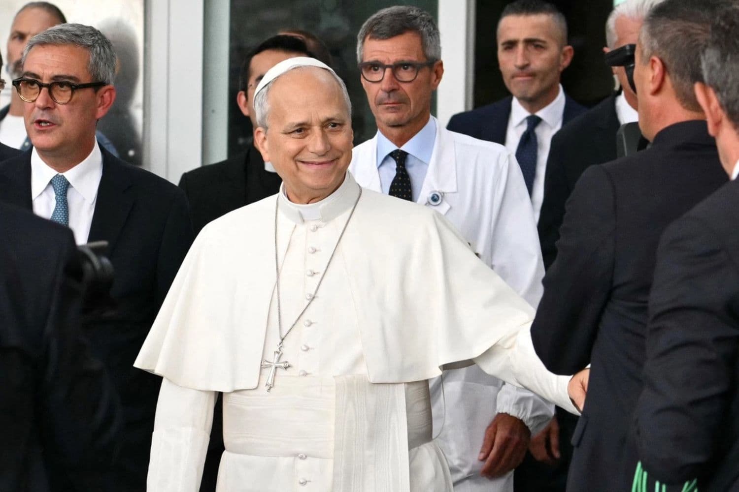 El papa León XIV, seguido por su cirujano Stefano Margaritora, saluda a la gente al salir del Hospital Universitario Gemelli, cuatro días después de una cirugía para extirpar un tumor canceroso de su pulmón derecho, en Roma, el 17 de octubre de 2026. (Alberto Pizzoli/AFP vía Getty Images)