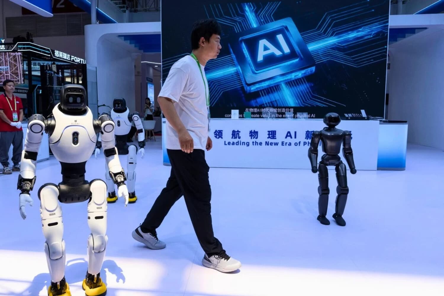 Un trabajador pasa junto a unos robots en la Exposición Internacional de la Cadena de Suministro de China, celebrada en Beijing, China, el 22 de junio de 2026. (Ng Han Guan/AP).