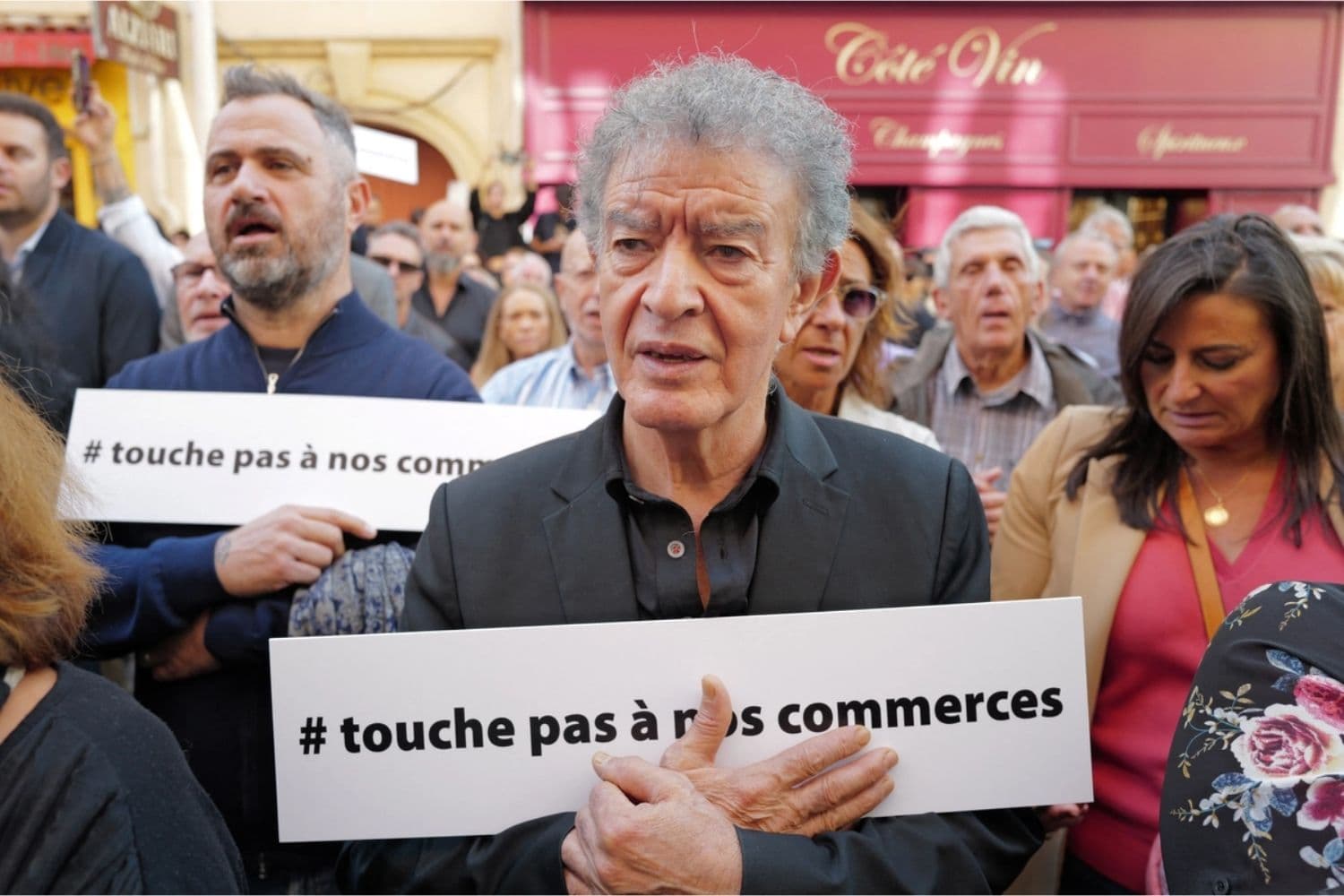 La gente sostiene pancartas con el lema "No toquen nuestras tiendas" mientras escucha al alcalde de Niza durante una manifestación en apoyo a todas las autoridades locales francesas, en Niza, Francia, el 19 de octubre de 2026, dos días después de los disturbios y saqueos en Francia. (Valery Hache/AFP vía Getty Images)