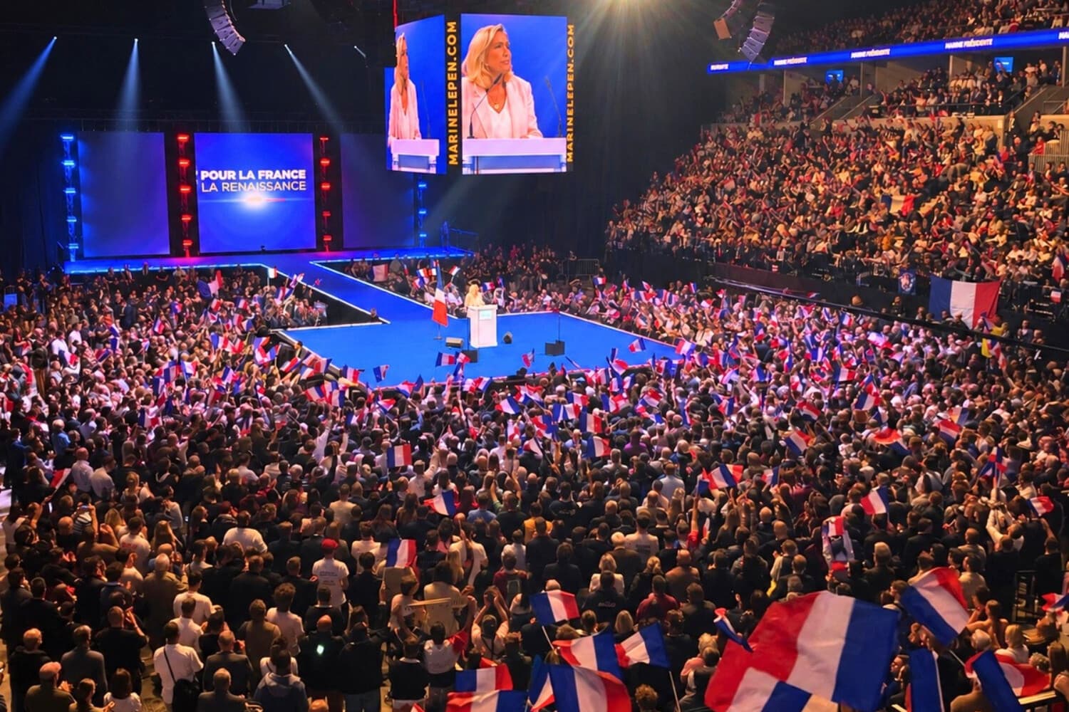 Marine Le Pen se dirige a una multitud de simpatizantes que agitan banderas francesas durante el lanzamiento de su campaña presidencial para 2027 en Orléans, Francia, el 25 de octubre de 2026. (Etienne Fauchaire/The Epoch Times).