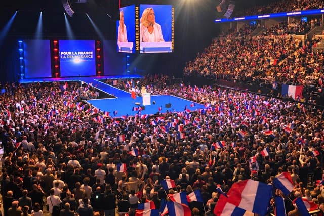 Marine Le Pen se dirige a una multitud de simpatizantes que agitan banderas francesas durante el lanzamiento de su campaña presidencial para 2027 en Orléans, Francia, el 25 de octubre de 2026. (Etienne Fauchaire/The Epoch Times).