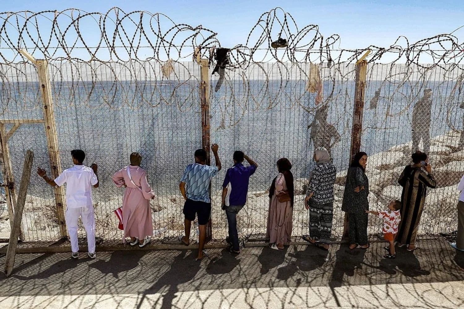 Familiares y amigos esperan junto a una cerca coronada con alambre de púas el regreso de las personas que habían cruzado anteriormente al enclave español de Ceuta, en el norte de África, en el paso fronterizo marroquí de Bab Sebta, en las afueras de Fnideq, el 2 de agosto de 2026. (Abdel Majid Bziouat/AFP vía Getty Images)